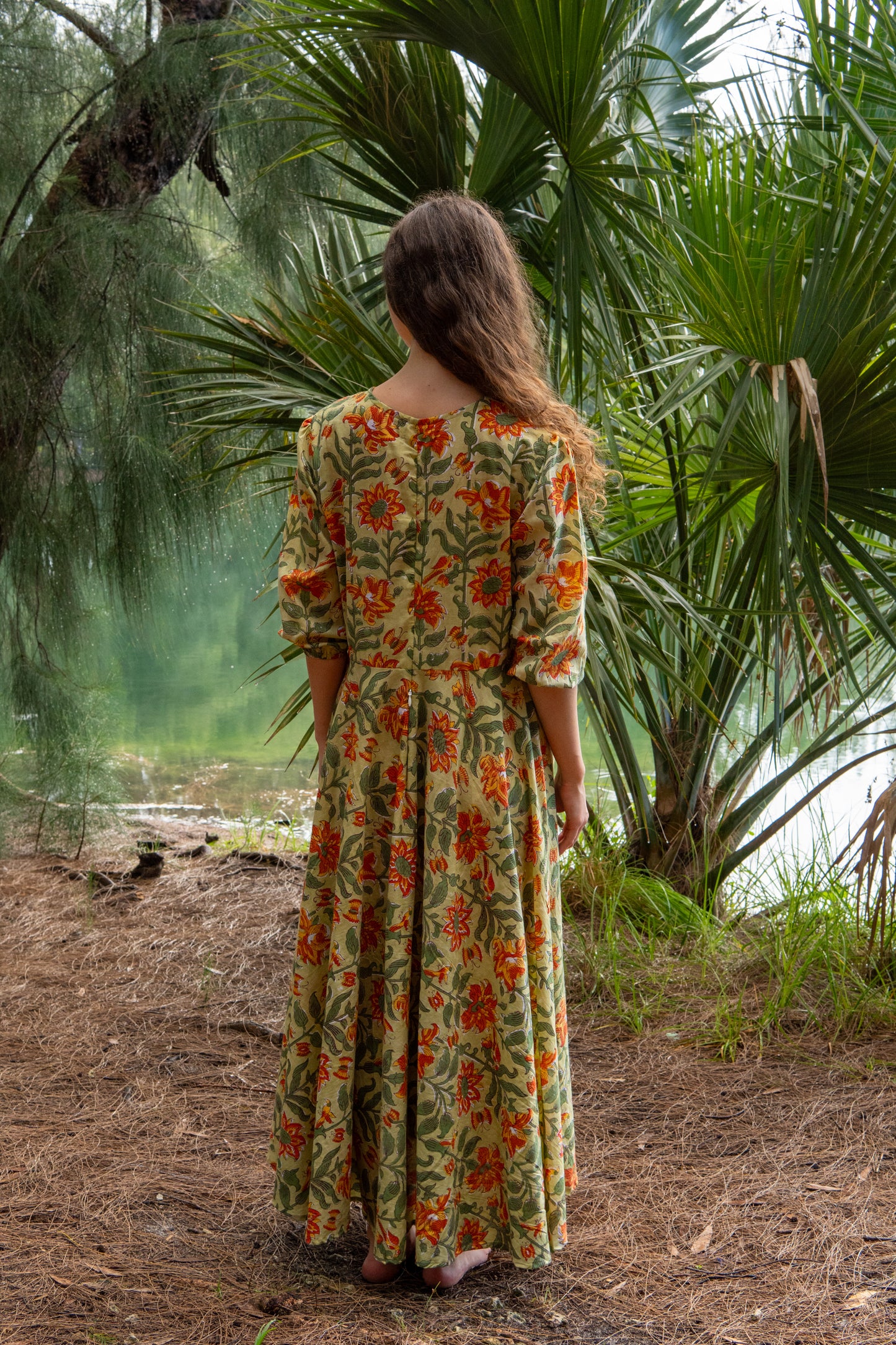 Woman in a floral dress standing in a forest setting