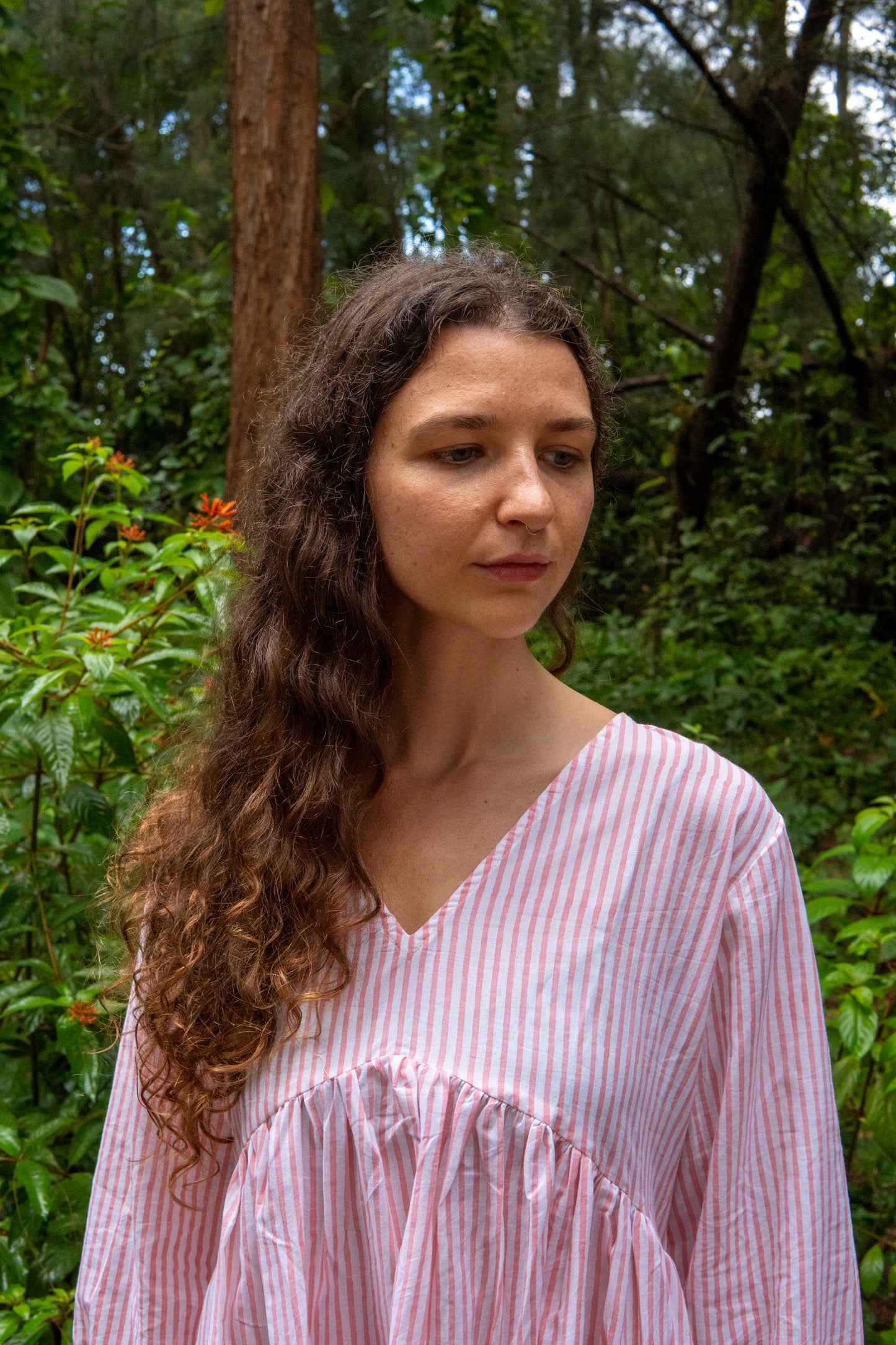 Woman in a pink striped dress standing in a forest