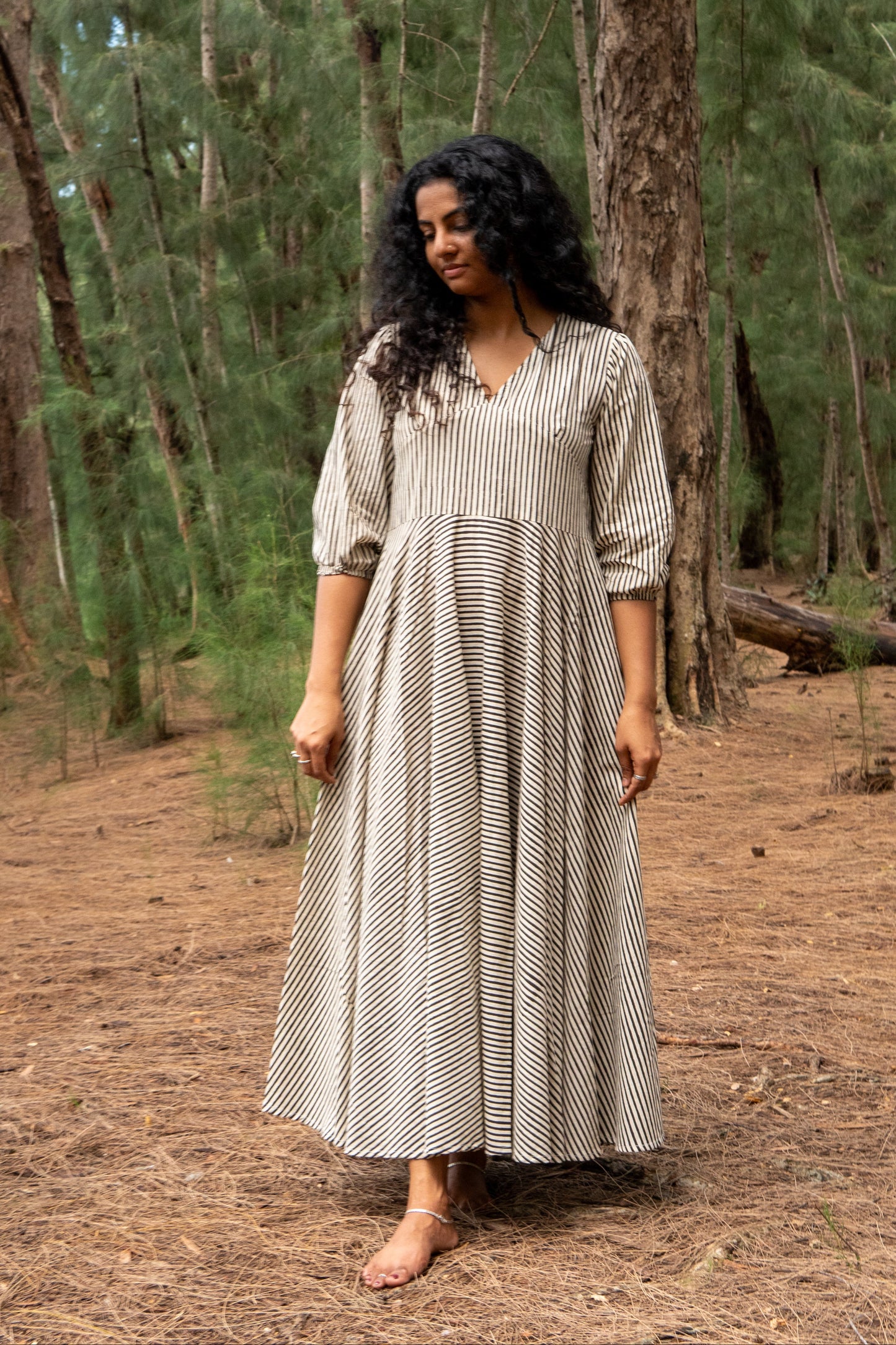 Woman in a long, patterned dress standing in a forest