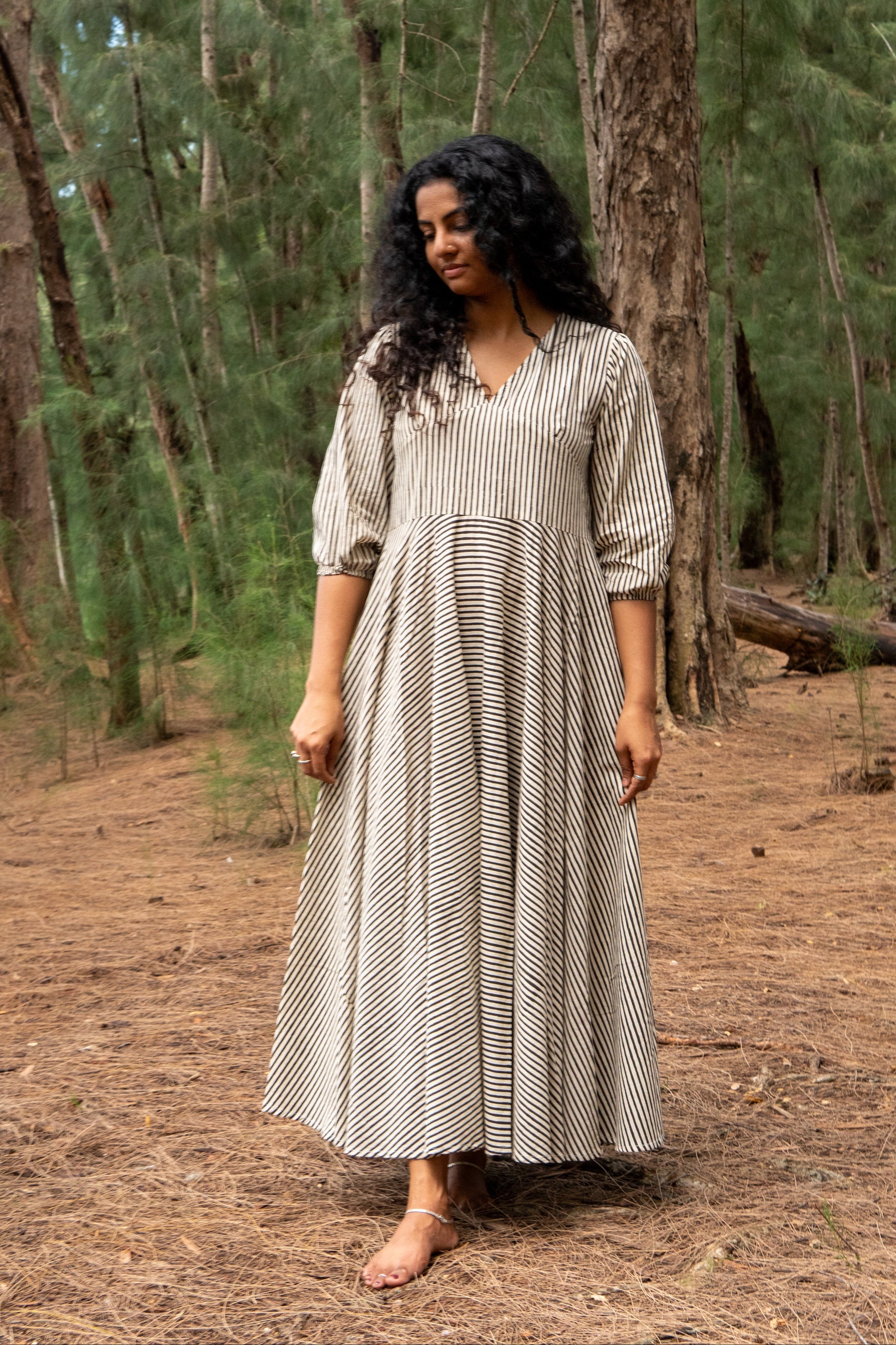 Woman in a long, patterned dress standing in a forest