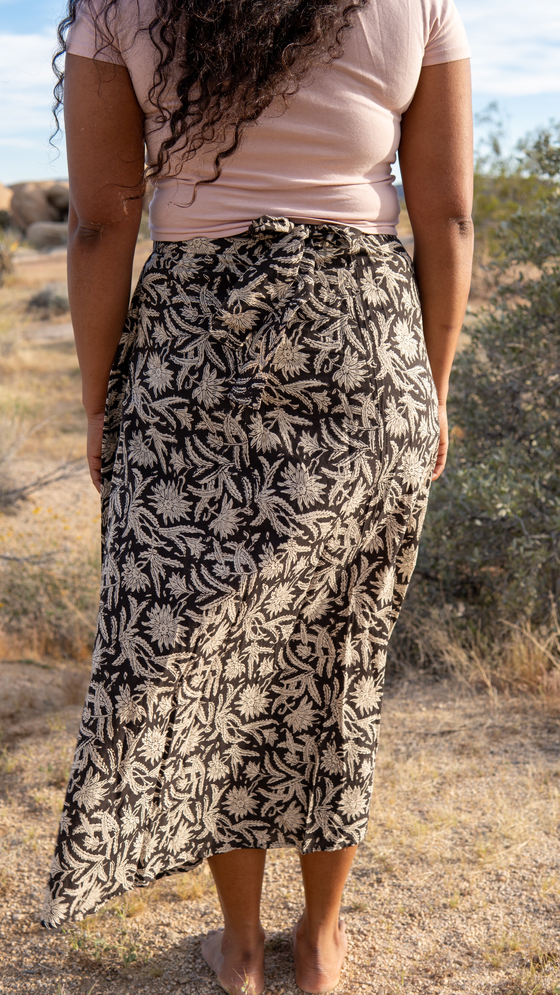 Person wearing a black and white floral skirt in a natural setting