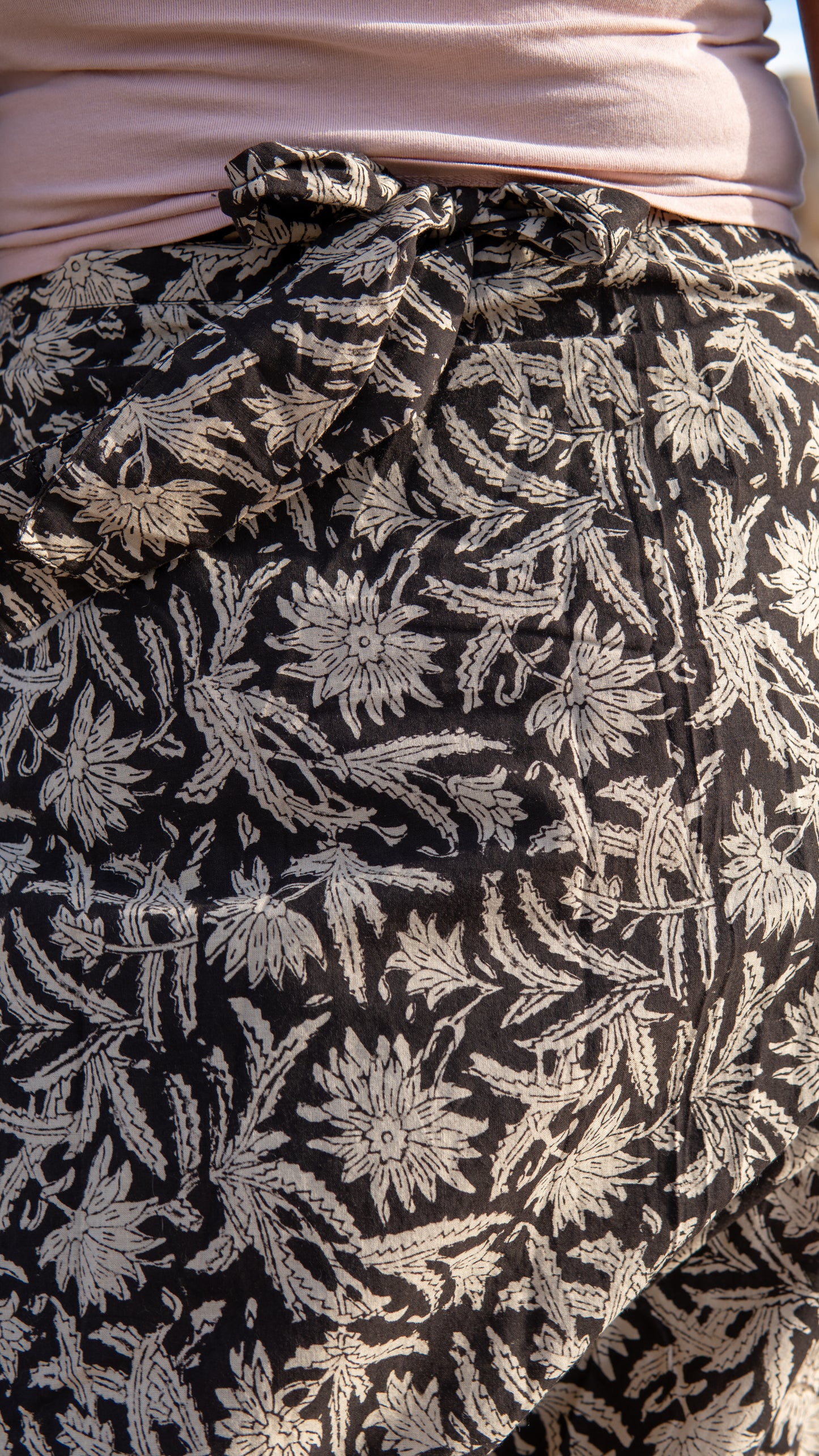 Close-up of a black fabric with white floral pattern, possibly a skirt or garment.