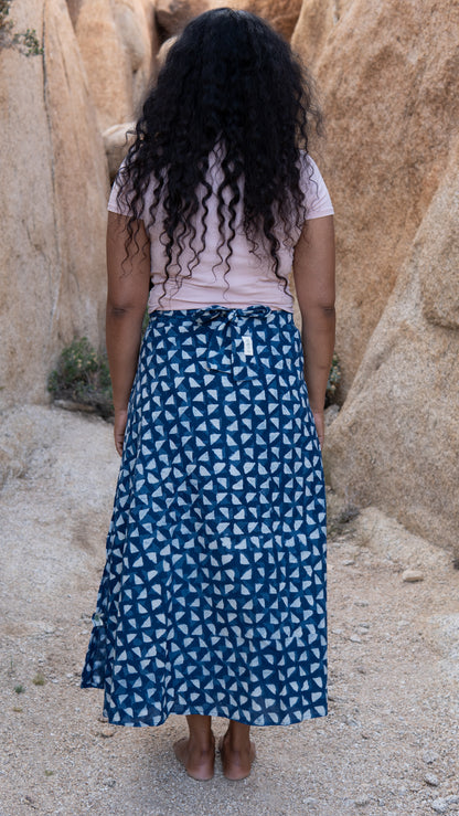 Person wearing a blue patterned skirt standing in a rocky desert landscape