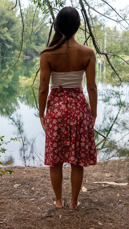 Woman in a red floral skirt standing by a lake