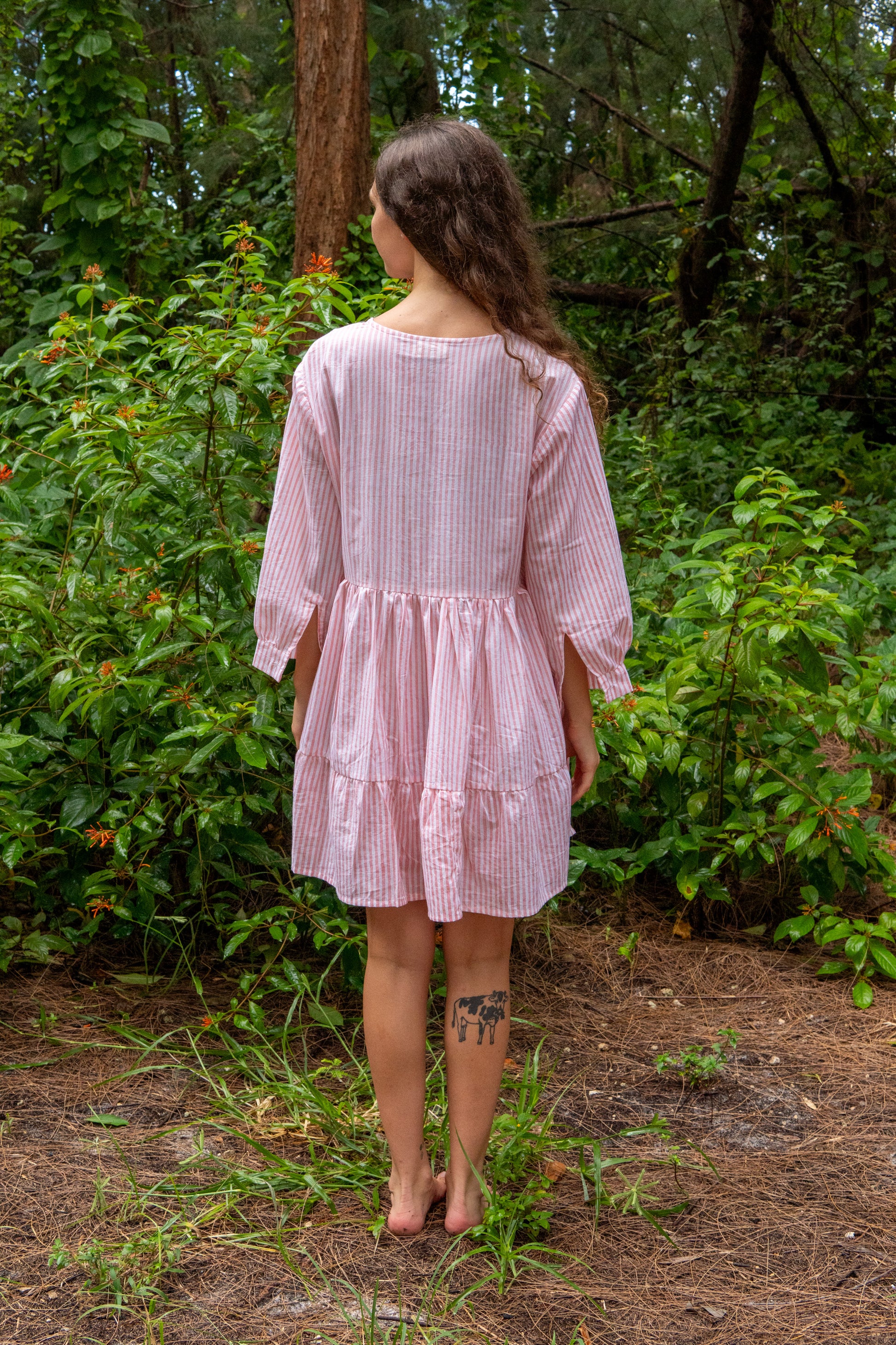 Woman in a pink dress standing in a forest