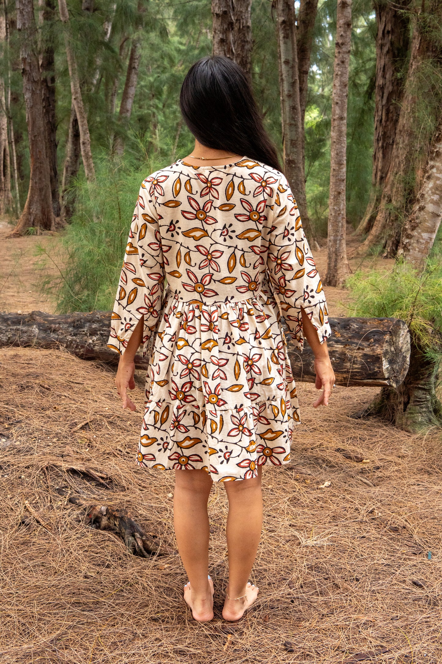Woman wearing a patterned dress walking through a forest