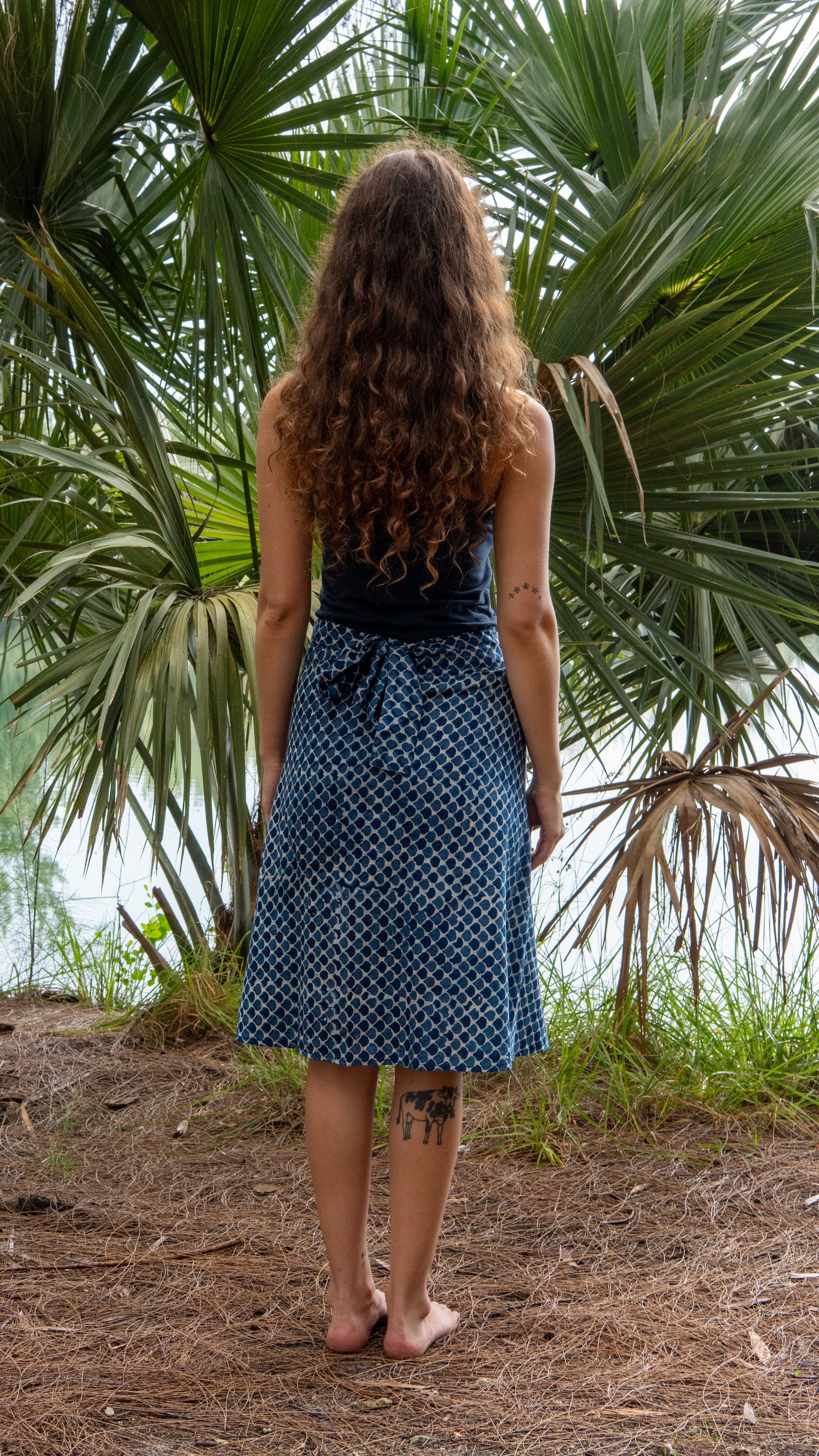 Woman in a blue dress standing in front of palm trees