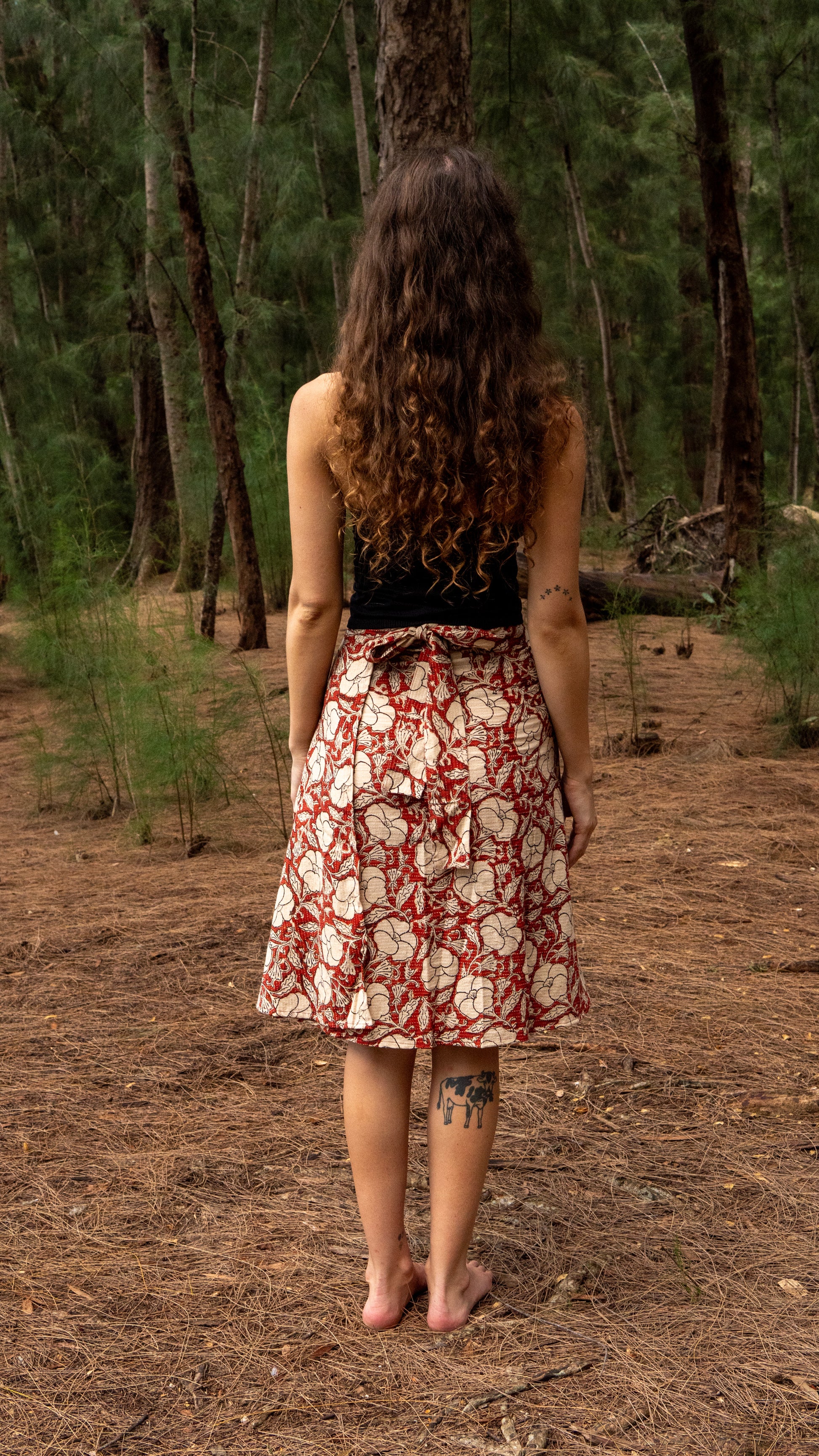 Person wearing a patterned dress standing in a forest