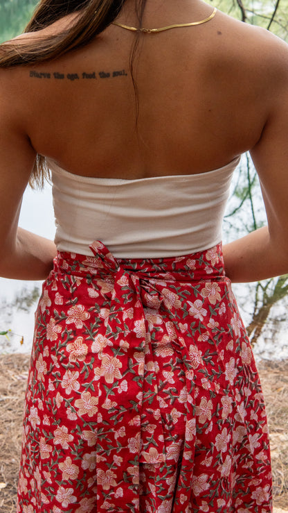 Person wearing a white top and red floral skirt with a natural background