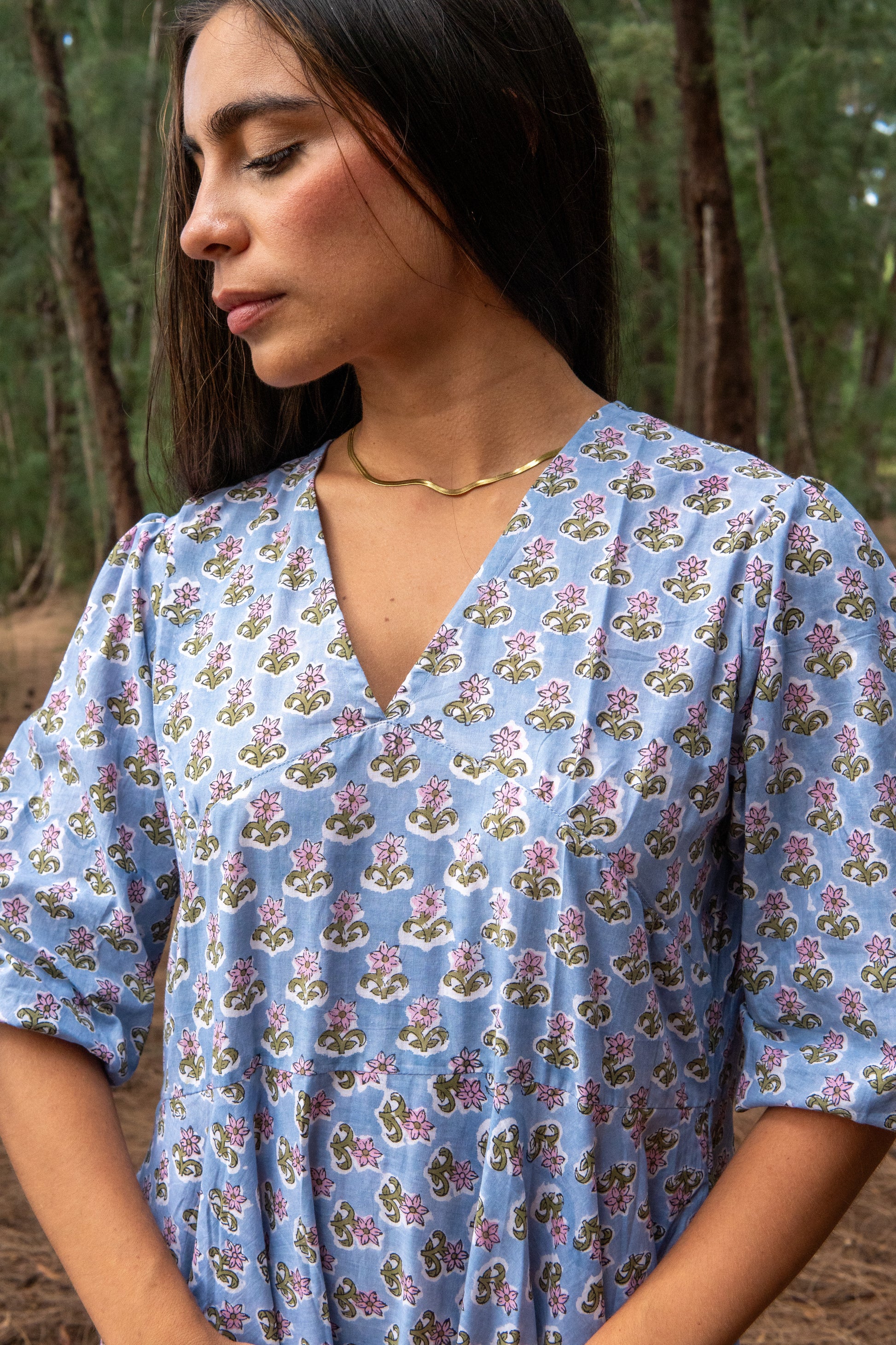 Woman wearing a blue floral dress in a forest setting