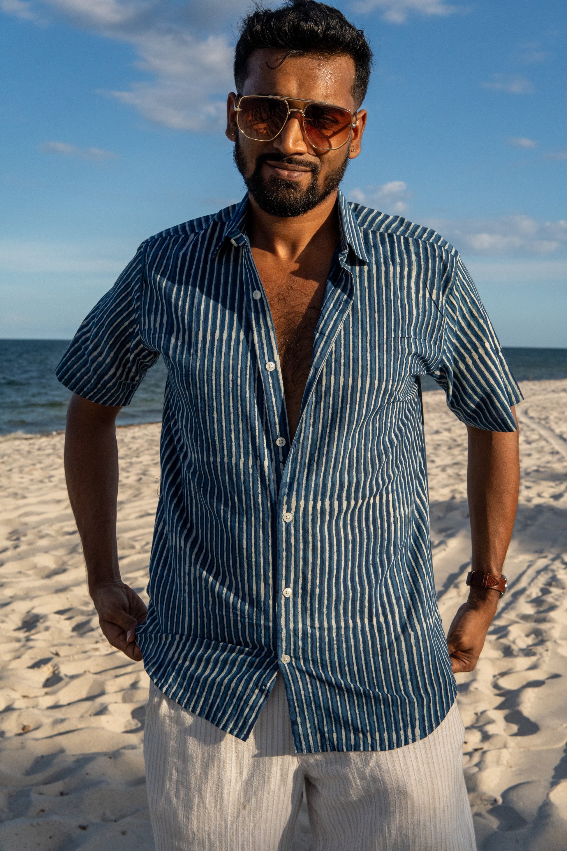 Man wearing sunglasses and a striped shirt on a beach