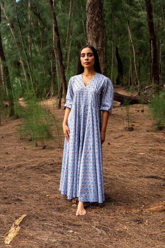 Woman in a blue patterned dress standing in a forest