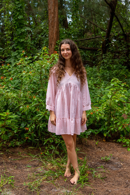 Woman in a pink dress standing in a forest setting