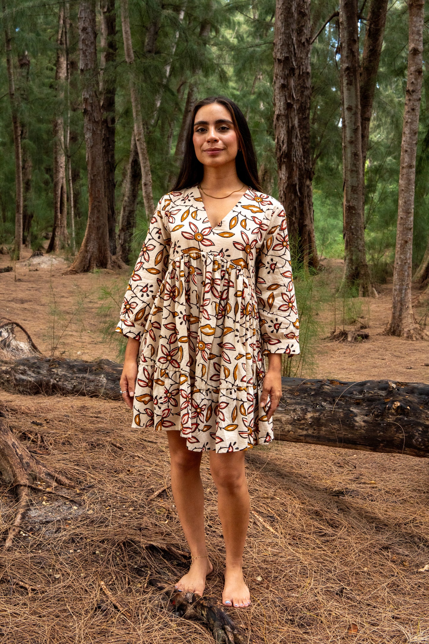 Woman in a patterned dress standing in a forest