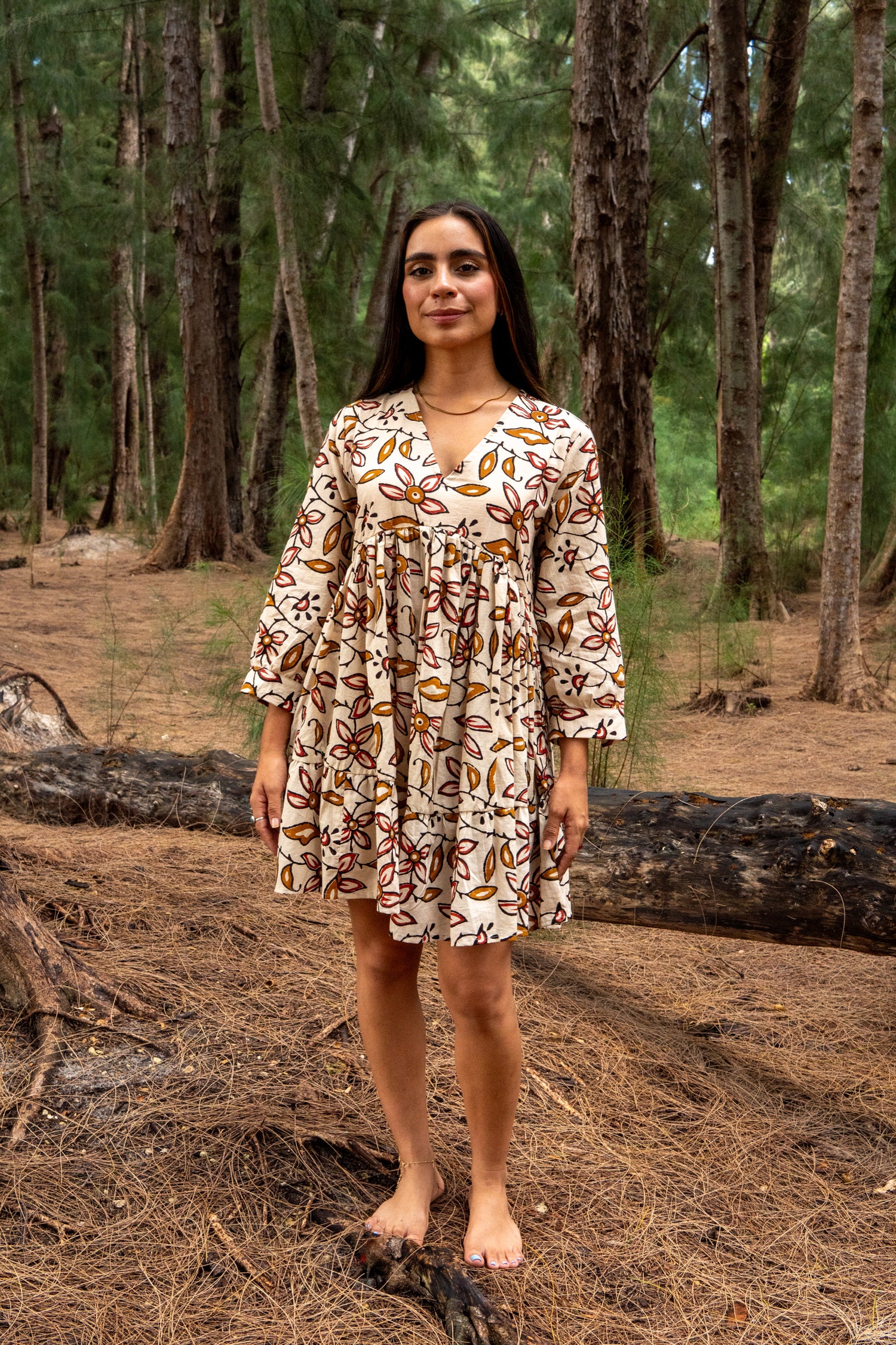 Woman in a patterned dress standing in a forest