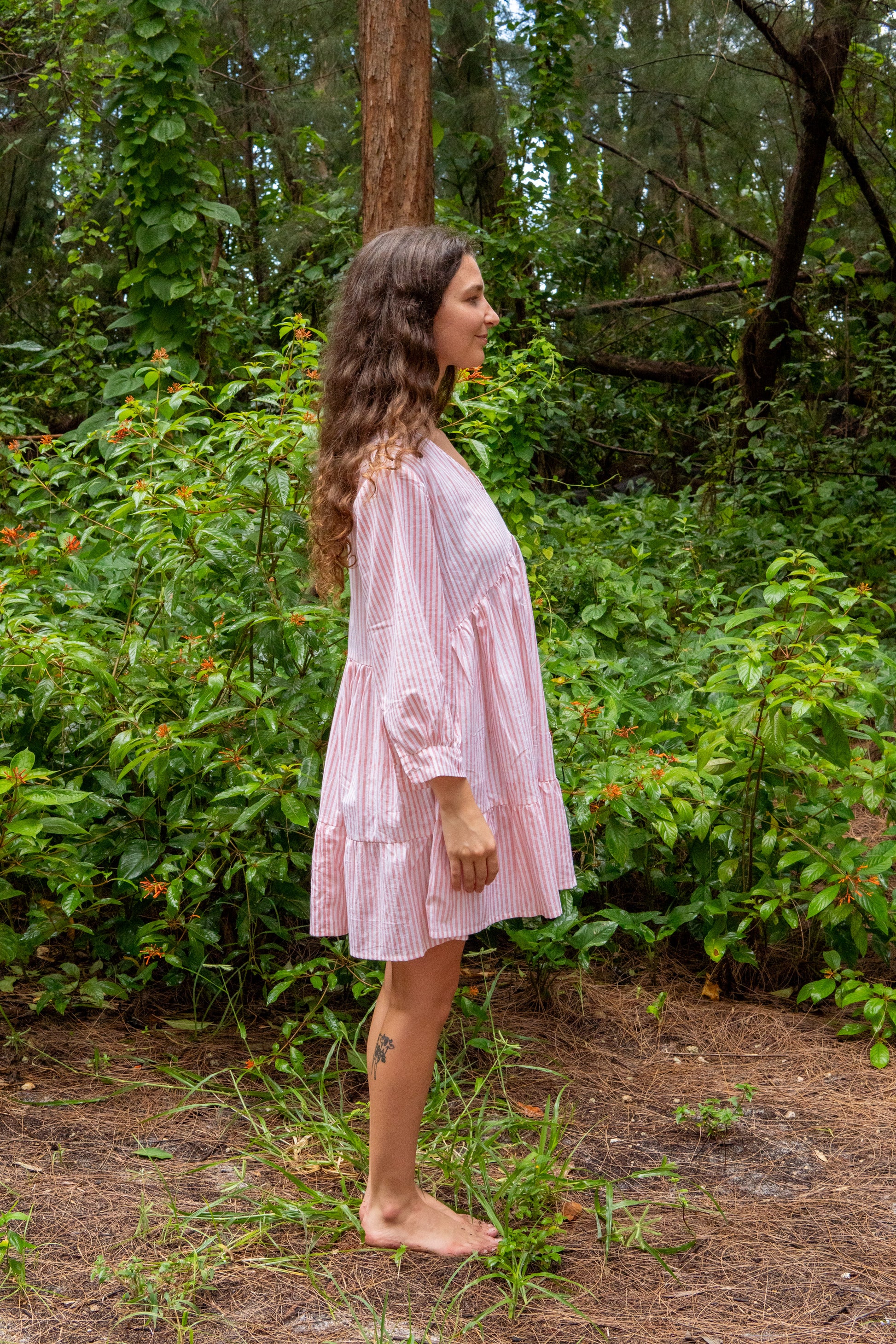 Woman in a pink dress standing in a forest setting