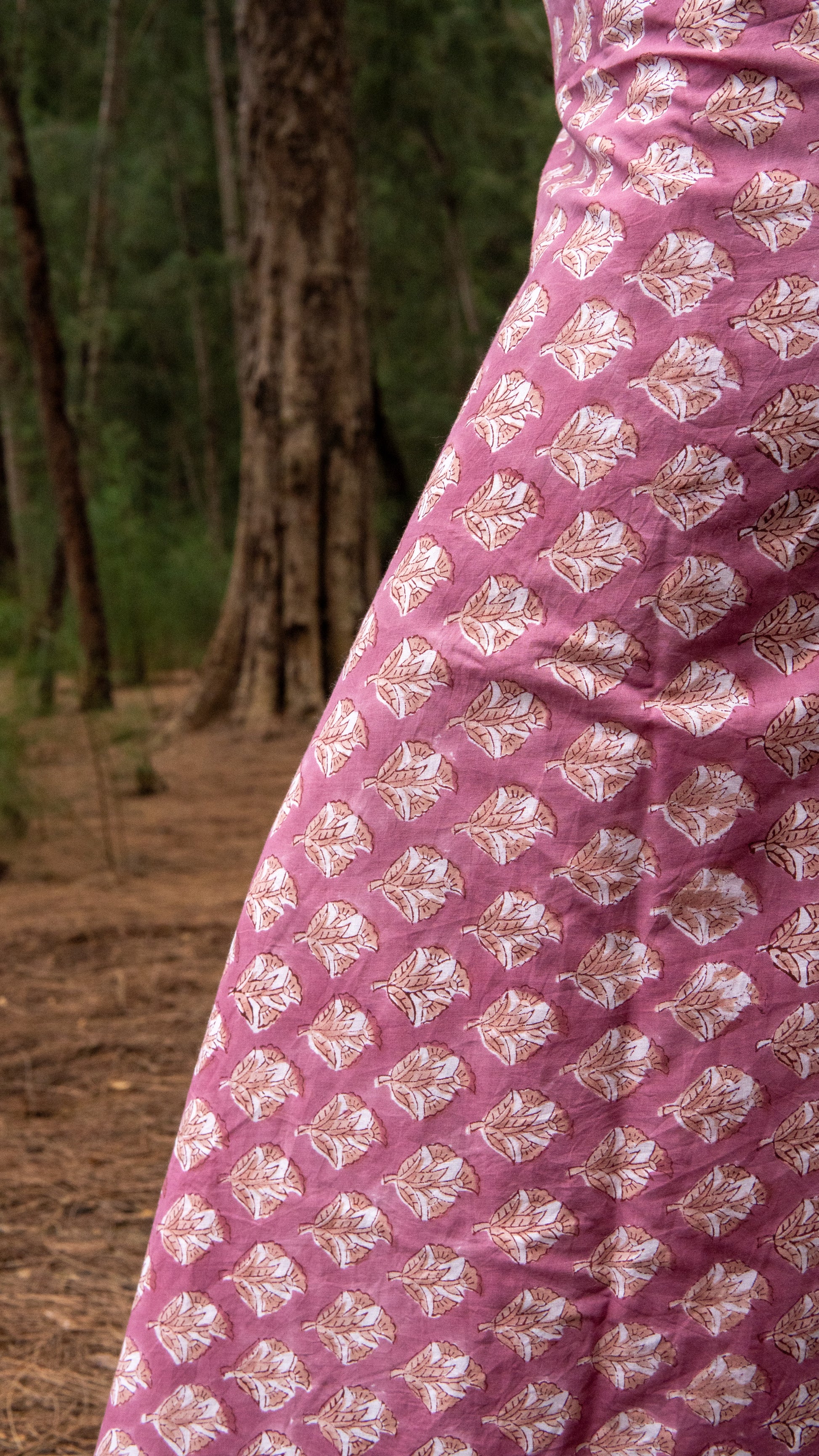 Close-up of a pink fabric with white floral patterns in a natural setting.