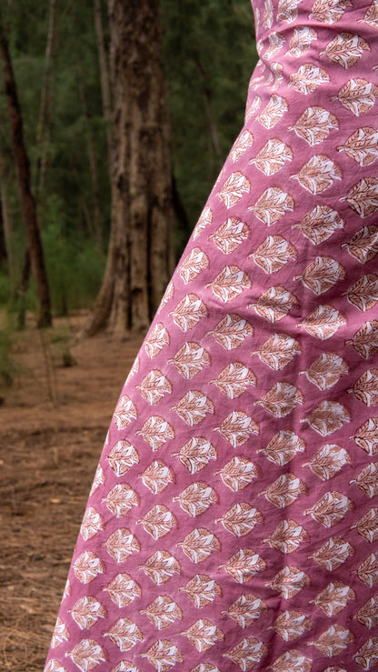 Close-up of a pink fabric with white floral patterns in a natural setting.