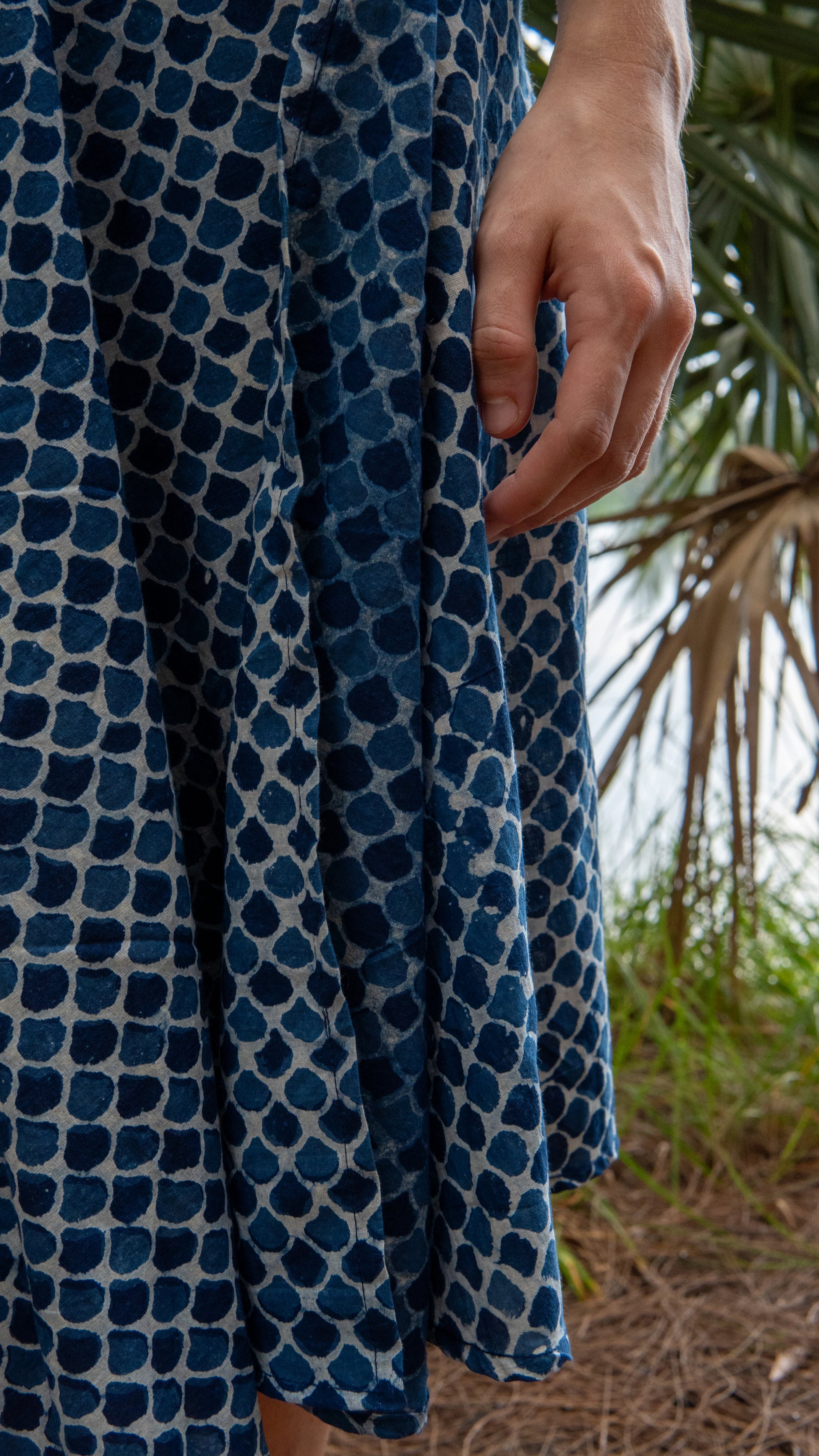 Close-up of a person wearing a blue patterned dress with a natural background